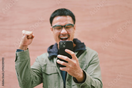 adult asian man using mobile, cell phone.portrait young male person posing smart phone smiling laughing look fun excited surprised happy.empty space for text advertising