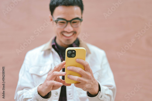 adult asian man using mobile, cell phone.portrait young male person posing smart phone smiling laughing look fun excited surprised happy.empty space for text advertising