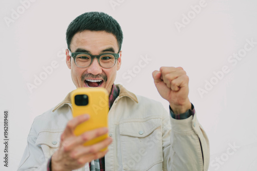 adult asian man using mobile, cell phone.portrait young male person posing smart phone smiling laughing look fun excited surprised happy.empty space for text advertising