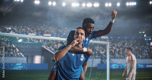 Black and Middle Eastern Male Soccer Teammates Celebrate a Vital Goal at the Net During a Professional International Tournament Match, With One Player on His Teammate’s Back as a Rival Walks Away.