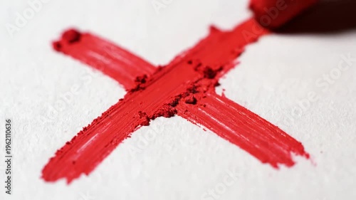 Hand painting red X mark on white paper with brush
