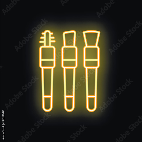 Makeup brushes glowing in yellow neon light on a black background