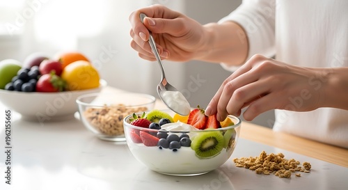 Hands prepare a colorful fruit and yogurt breakfast bowl.