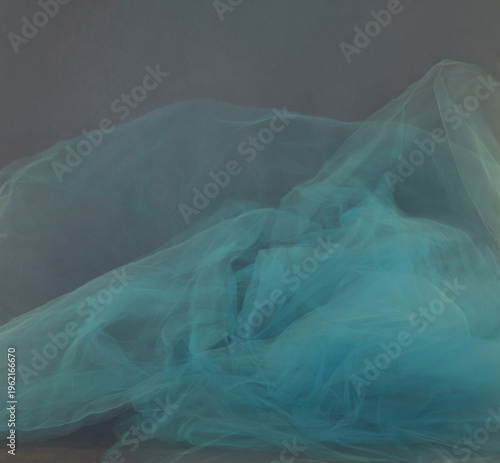 Soft blue tulle blur motion on dark background. Abstract airy cyan smoke mist fluidity overlay.