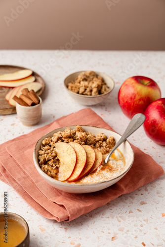 Foto Healthy breakfast bowl with yogurt, crunchy granola, sliced apples and cinnamon on a pink napkin