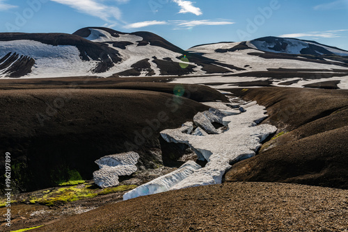 Foto Winding snow fields melting in a dark volcanic canyon, Iceland.
