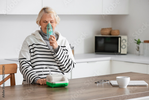 Senior woman using nebulize...