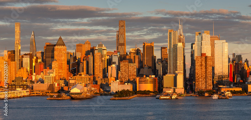 Golden hour view of Midtown Manhattan skyline along the Hudson River, New York City, USA. Skyscrapers and urban waterfront cityscape in warm sunset light