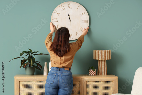 Young woman hanging clock o...
