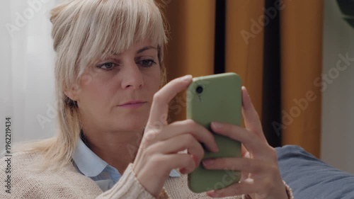 Focused blonde woman texting on smartphone