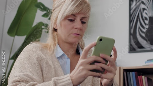 Mature blonde woman using smartphone at home