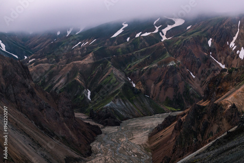 Foto Dark mountain ridges with snow patches fading into mountain mist.
