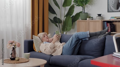 Woman relaxing on couch using smartphone