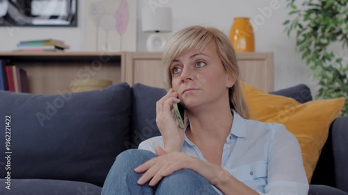 Blonde woman talking on smartphone at home