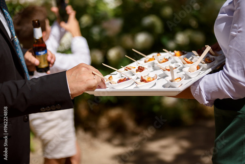 Quadro su tela Close-up of a waiter serving appetizers on a tray during an outdoor business eve