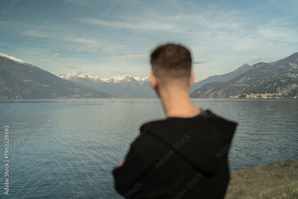 Fototapeta premium Traveler standing back view looking at Alpine mountains and Lake Como landscape in Lombardy Italy.