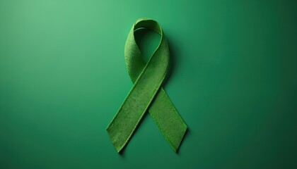 Green ribbon on plain green background symbolizes health awareness for various causes. Use for campaigns promoting support and care for diseases and disorders.