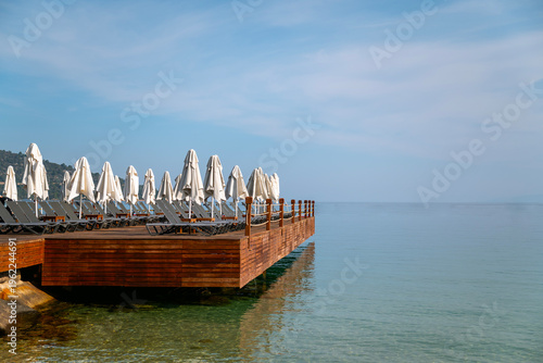 Wooden Pier with sunbeds and umbrellas above the sea 