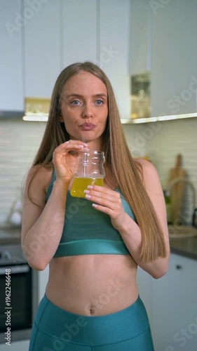 Fit woman drinking healthy yellow juice in her kitchen