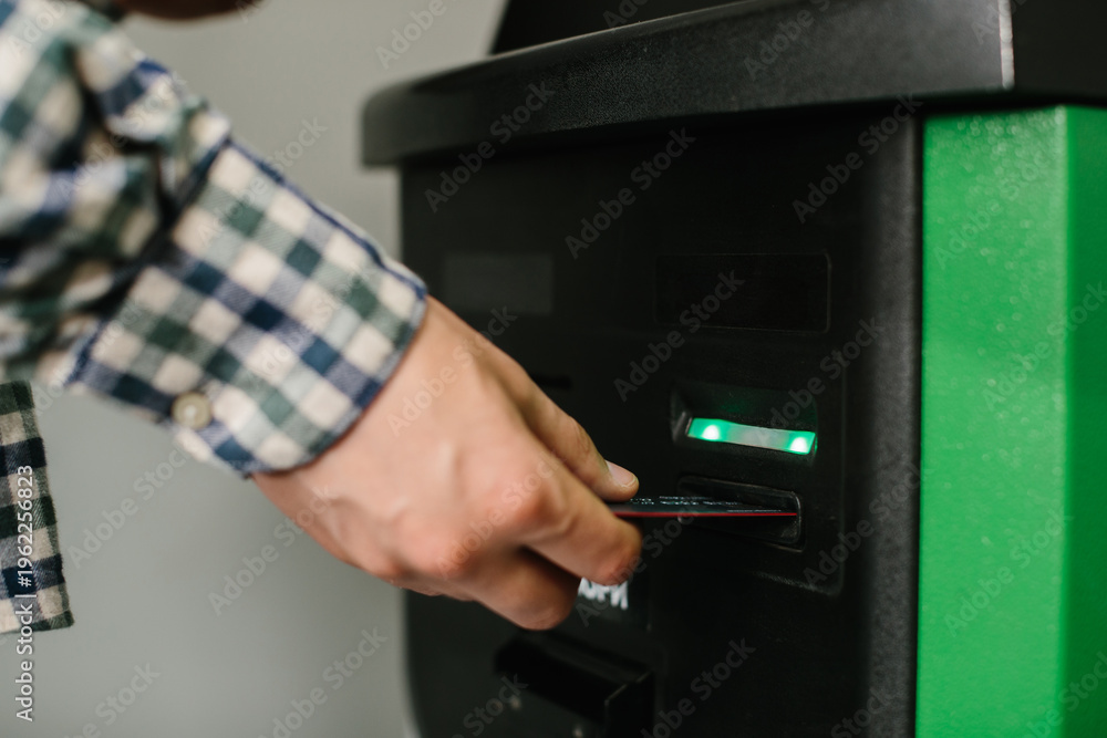 Obraz premium Person inserting bank card into atm for transaction
