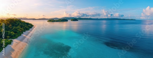 White sand tropical beach with lush green forest meeting clear turquoise ocean water, small islands and calm sea