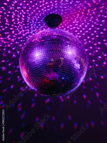disco ball with mirror surface and bright rays, purple color, hanging on ceiling, night party background