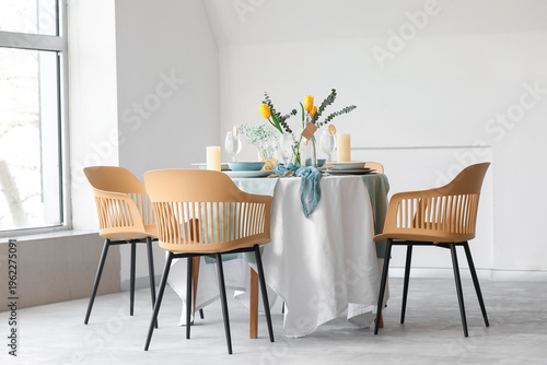 Elegant table setting with beautiful tulip flowers and candles in light dining room