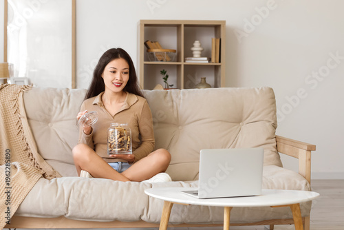 Young woman sitting on sofa...