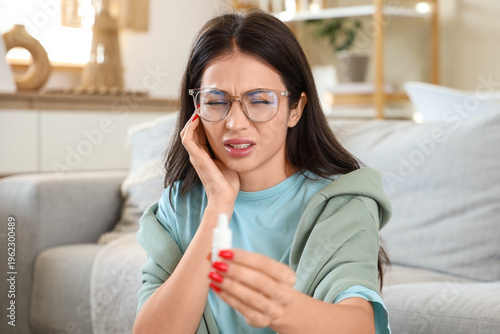Young woman with ear drops ...