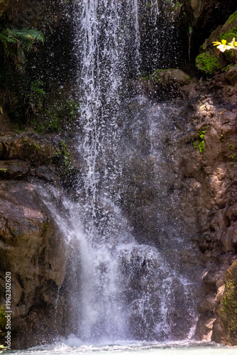 Alam Kandung Waterfall in Indonesia with cascading water and tropical forest backdrop. Bright natural colors highlight the beauty of this serene landscape.