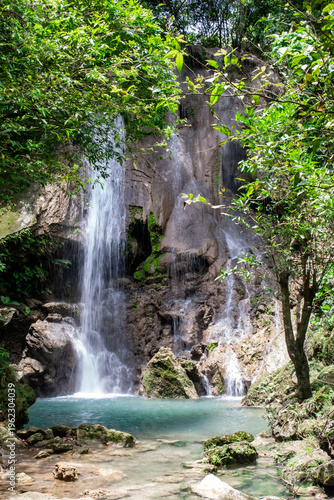 Alam Kandung Waterfall with white cascades pouring into a turquoise basin. Tropical greenery and rugged rocks create a serene natural landscape in Tulungagung.