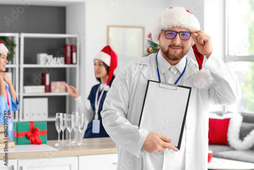 Male doctor in Santa hat wi...