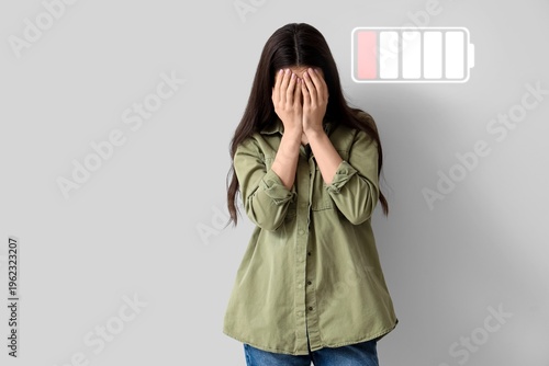 Tired young woman on grey b...