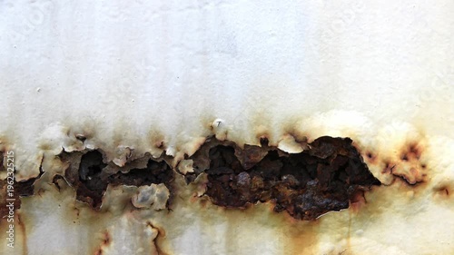 Close-up of a heavily rusted metal surface with peeling paint, showing industrial decay and oxidation textures in a seamless loop style.