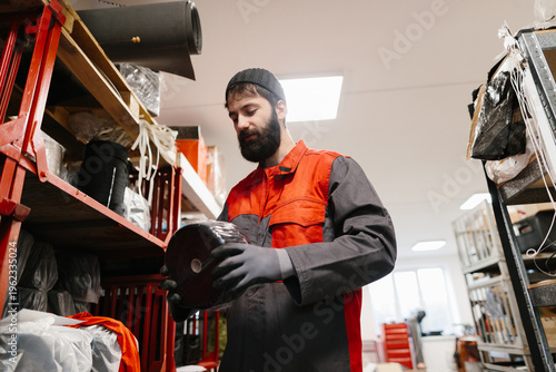 Φωτογραφία Worker inspecting material roll in industrial warehouse