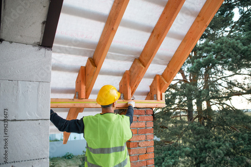Konstfotografi Construction site master checks evenness of rafters for insulated roof, modern build in progress, timber lag placement visualized