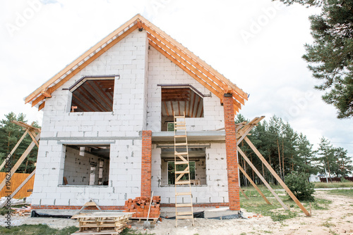 Fotografia Contemporary home with exposed rafter system, roof lag installation in progress, light facade, European architectural style, active construction