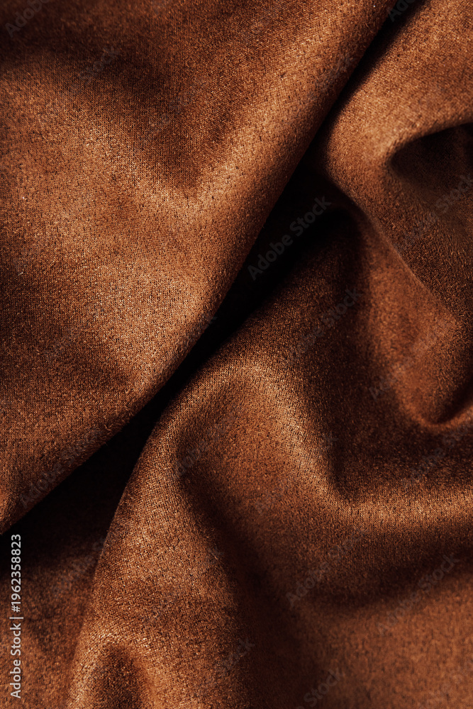 Fototapeta premium Soft brown fabric showing folds and texture under natural light in a simple indoor setting during daytime