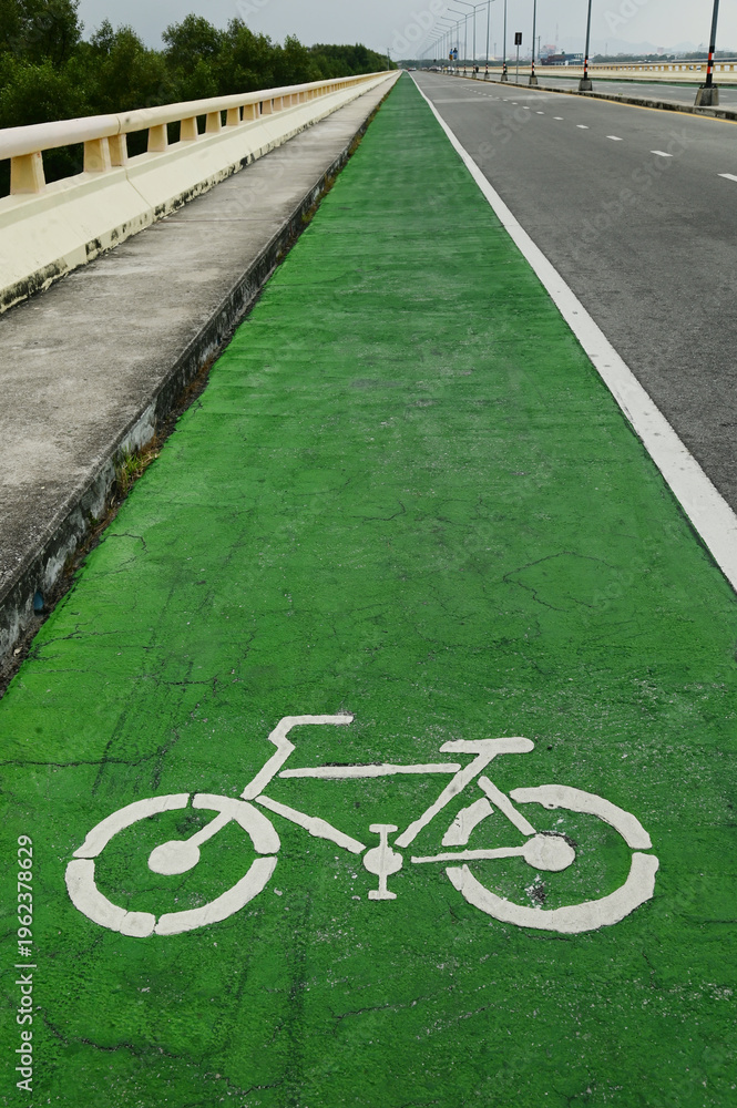 Obraz premium Urban Cycling Path Green Lane with the Bikeway Symbol on asphalt pavement. Street scene for eco transportation, commuting, or city infrastructure.