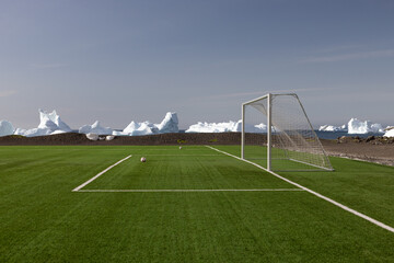 Soccer goal on green field with icebergs in the background on Disko Island in Greenland