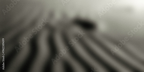 Foto A blurry black and white photo of a striped surface with a dark object in the ba