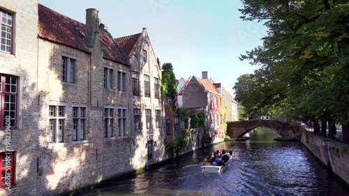 Bruges, Belgium – September 14, 2024 – Historical Boat Tour on the Groenerei Canal Bruges Belgium 4K UHD. Scenic tourist canal tour on the Groenerei canal near the Meebrug stone bridge. Bruges.