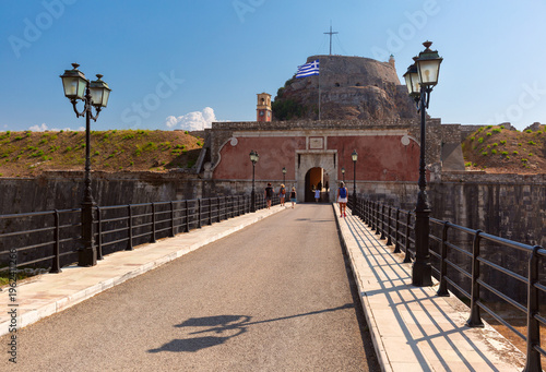 Old Fortress entrance with Greek flag and historic walls in Corfu Town, Greece.