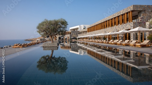 Modern resort architecture with a reflective pool and ocean view on a sunny day