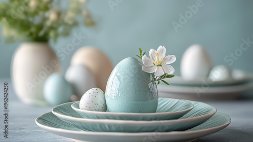 A beautiful Easter table setting features pastel colored eggs on plates, accentuated with a delicate white flower and a soft, muted background showcasing sp decor.