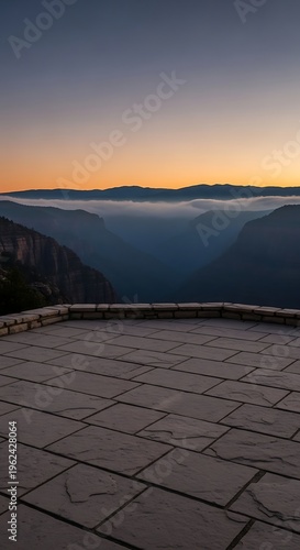 Sunrise over a misty canyon with a stone patio in the foreground offering a scenic viewpoint for nature exploration and travel.