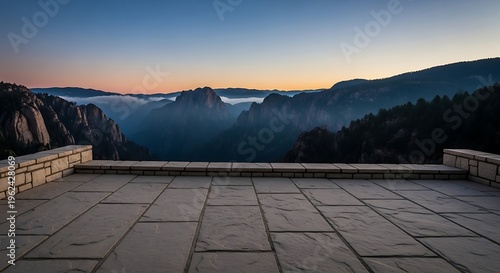 Scenic mountain vista at sunrise with a stone patio overlook offering a breathtaking view of misty valleys and rugged peaks