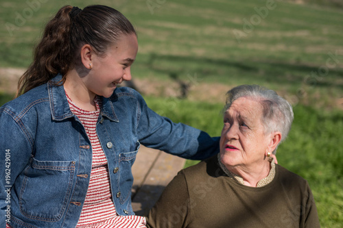 Granddaughter supporting grandmother outdoors, sharing a happy moment