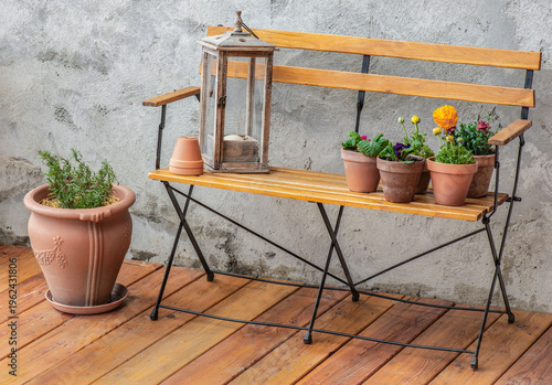 bench against the textured gray wall of a wooden terrace with a potty chair a...