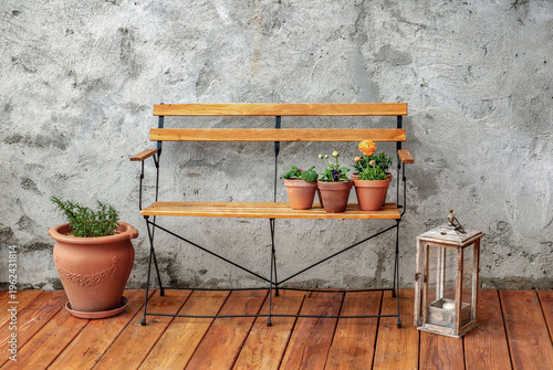 front of view on bench against the textured gray wall of a wooden terrace wit...